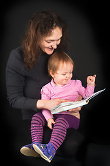 Image showing Pretty mother with daughter reading book with tales