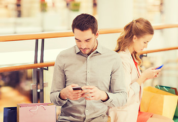 Image showing couple with smartphones and shopping bags in mall