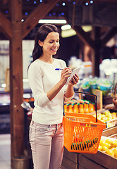 Image showing happy woman with food basket and notepad in market