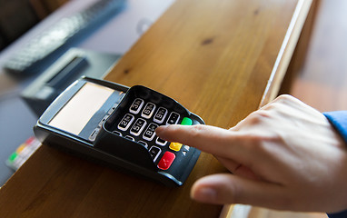 Image showing hand entering password to bank terminal