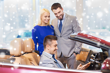 Image showing happy couple with car dealer in auto show or salon