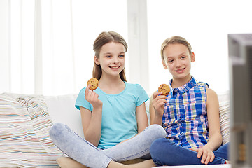 Image showing happy girls watching tv and eating cookies at home