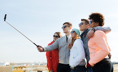 Image showing friends taking selfie with smartphone on stick