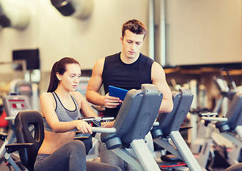 Image showing woman with trainer on exercise bike in gym