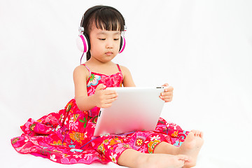 Image showing Chinese little girl on headphones holding tablet