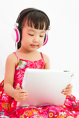 Image showing Chinese little girl on headphones holding tablet