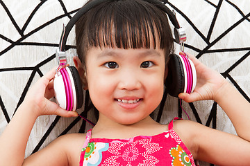 Image showing Chinese little girl on headphones holding mobile phone