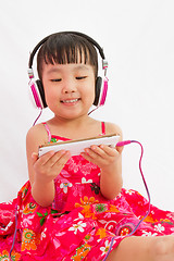 Image showing Chinese little girl on headphones holding mobile phone