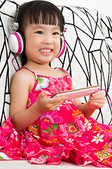 Image showing Chinese little girl on headphones holding mobile phone