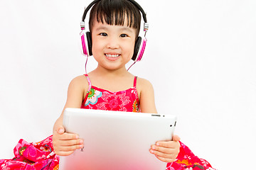 Image showing Chinese little girl on headphones holding tablet
