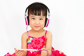 Image showing Chinese little girl on headphones holding mobile phone