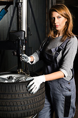 Image showing Young trainee changing  car tyre 