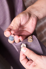 Image showing dressmaker sews a button on jacket