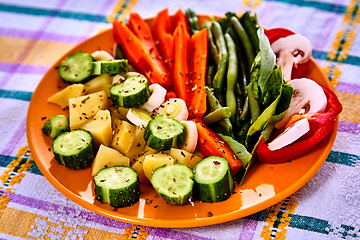 Image showing Ladle of steamed freshly harvested young vegetables including crinkle cut sliced carrots, peas and potato batons