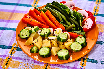 Image showing Ladle of steamed freshly harvested young vegetables including crinkle cut sliced carrots, peas and potato batons