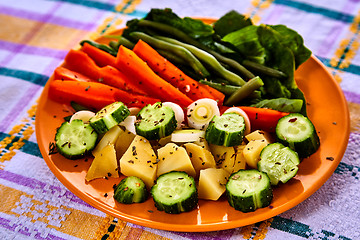 Image showing Ladle of steamed freshly harvested young vegetables including crinkle cut sliced carrots, peas and potato batons