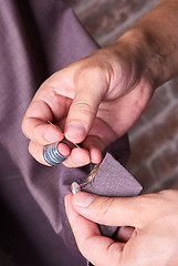 Image showing dressmaker sews a button on jacket