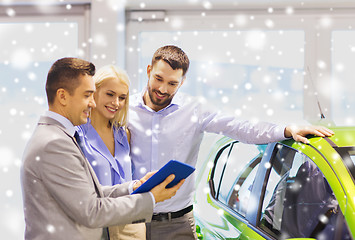 Image showing happy couple with car dealer in auto show or salon