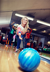 Image showing happy young woman throwing ball in bowling club