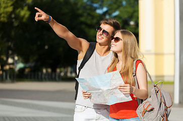 Image showing smiling couple with map and backpack in city