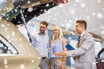 Image showing happy couple with car dealer in auto show or salon