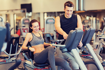 Image showing happy woman with trainer on exercise bike in gym