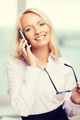 Image showing smiling businesswoman with smartphone in office