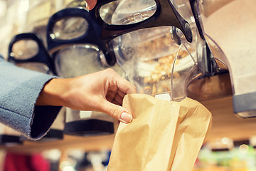 Image showing close up of hand pouring nuts to paper bag