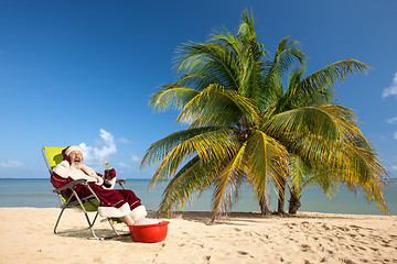 Image showing Santa Claus sitting in deck chair on beach