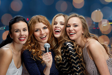 Image showing happy young women with microphone singing karaoke