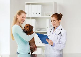 Image showing happy woman with dog and doctor at vet clinic