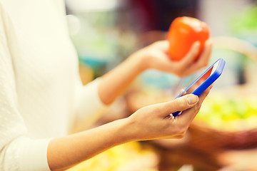 Image showing woman with smartphone and persimmon in market