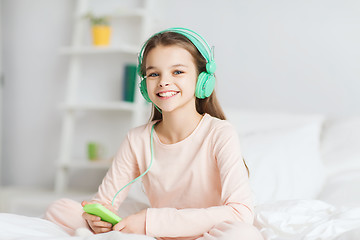Image showing girl sitting on bed with smartphone and headphones