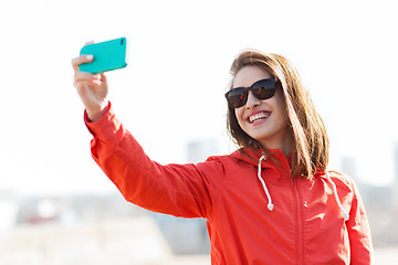 Image showing smiling young woman taking selfie with smartphone
