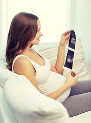 Image showing happy pregnant woman with ultrasound image at home