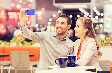 Image showing happy couple with smartphone taking selfie in mall