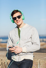 Image showing happy young man in headphones with smartphone