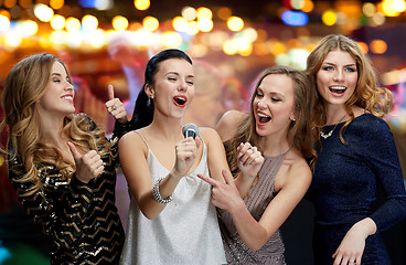 Image showing happy young women with microphone singing karaoke