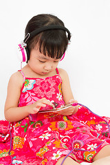 Image showing Chinese little girl on headphones holding mobile phone