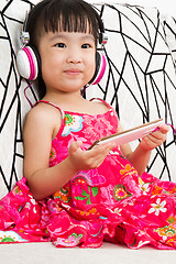 Image showing Chinese little girl on headphones holding mobile phone