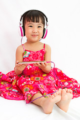 Image showing Chinese little girl on headphones holding mobile phone