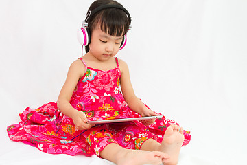 Image showing Chinese little girl on headphones holding tablet