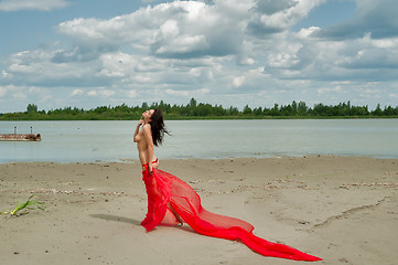 Image showing Attractive naked girl with red scarf on sand