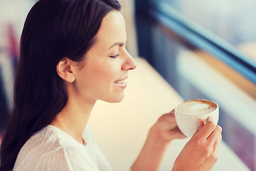 Image showing smiling young woman drinking coffee at cafe