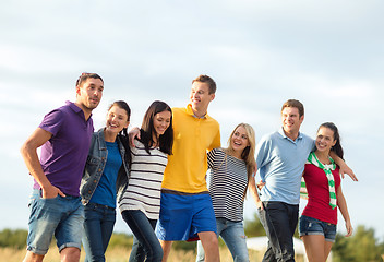 Image showing group of happy friends walking along beach