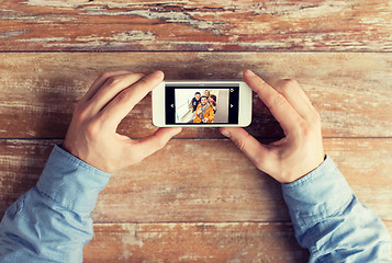 Image showing close up of male hands with photo on smartphone