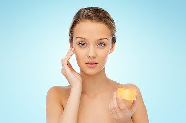 Image showing young woman applying cream to her face