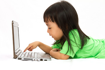 Image showing Chinese little girl lying down with laptop