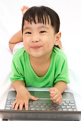 Image showing Chinese little girl lying down with laptop