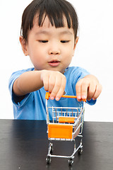 Image showing Chinese little girl pushing a toy shopping cart